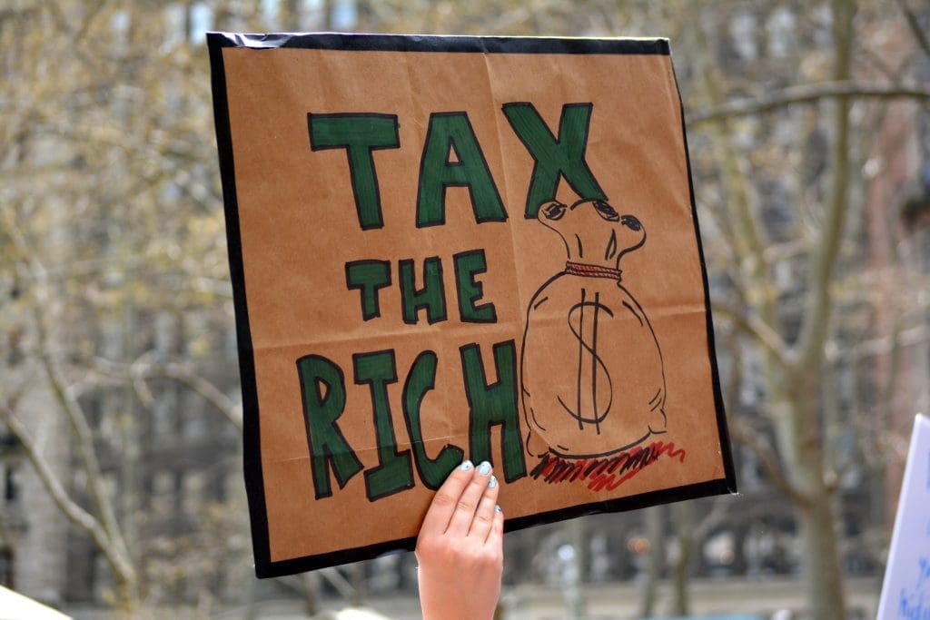 EU study shows how to raise $500bn a year for sustainable development 3 A protestor holding a placard that says 'tax the rich'