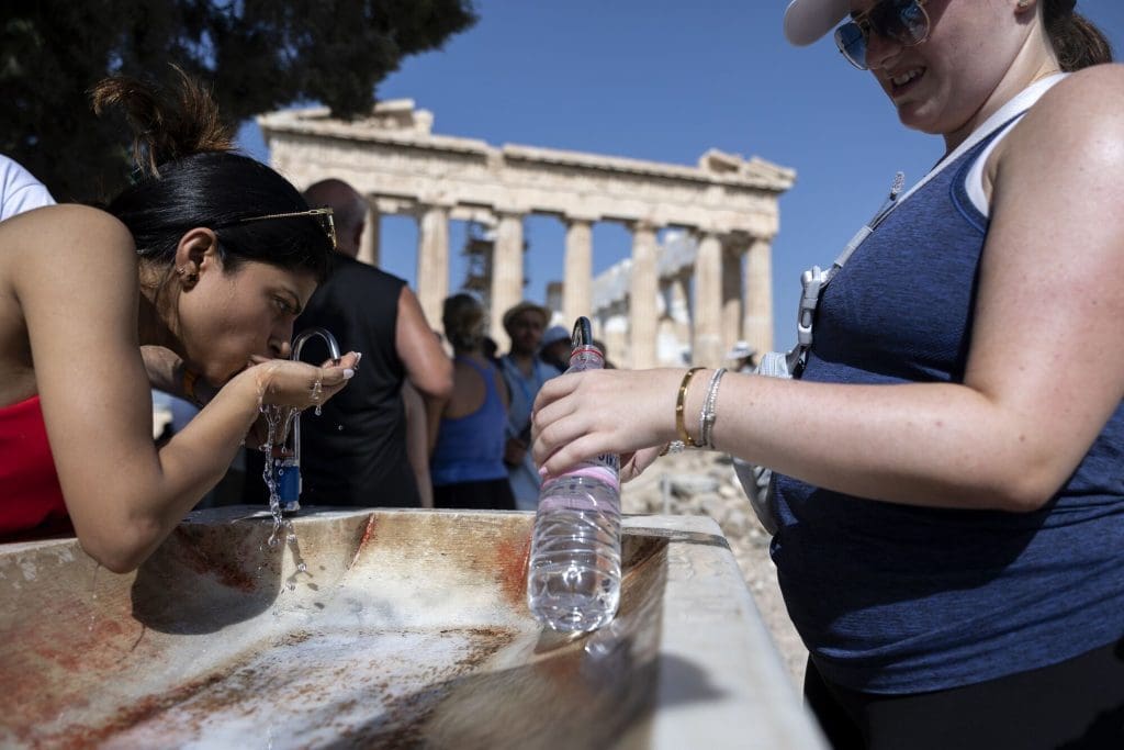 People filling water bottles at a fountain in Greece during a heatwave