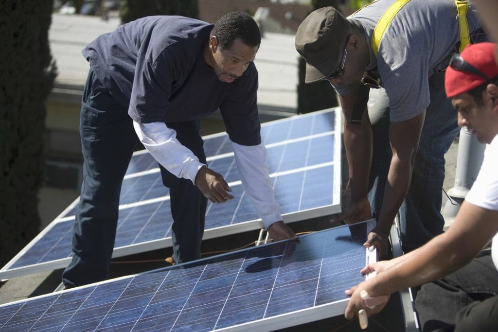 Three men install a rooftop solar system. These systems reduce the energy burden experienced by low-income households, a study has found.