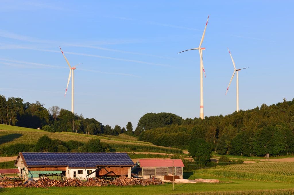 EU approves €1.8 billion in compensation for early coal plant closures in eastern Germany 6 A photo of a farm in Germany with solar panels on the roof of the home and wind turbines in the background.