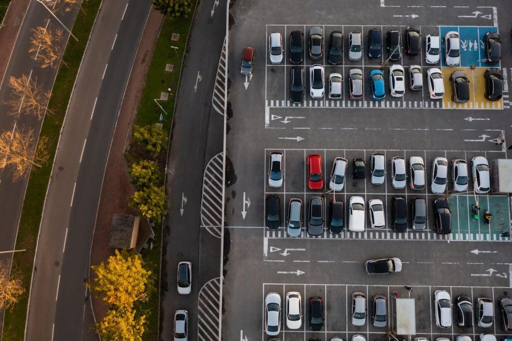 An aerial view of a parking lot, which takes up a huge amount of space and costs cities financially.