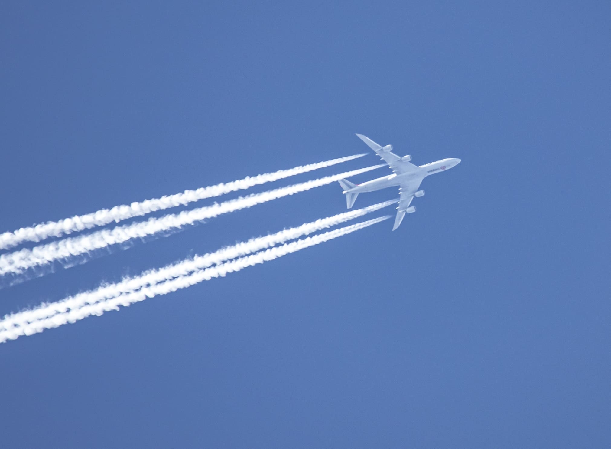 A photo of contrails behind a plane. Contrails contribute to climate change.